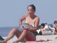 Spy video capturing and unsuspecting mature woman taking her top off at the beach