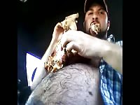 Weird selfie video of a bearded hairy dude eating a big chicken off of his chubby stomach