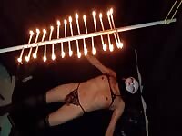 Candles are hanging on her body with an anal plug in